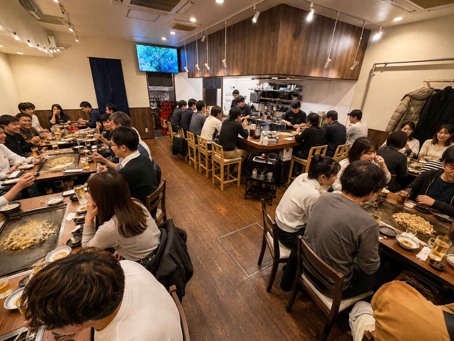 店内に多くのお客様が集まり、鉄板を囲んで食事を楽しむ様子